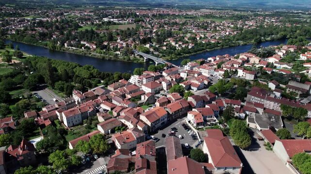 aerial shot over Saint Just Saint Rambert city center revealing the bridge crossing the Loire river and the Monts du Forez in the background, Loire departement, Auvergne Rhone Alpes region, France