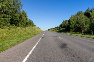 Fototapeta premium an empty straight paved road against a blue sky background
