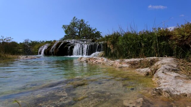 Wadi Darbat oasis, waterfalls, and natural spring with sparkling, clear water in Oman near Salalah - low angle with blue sky