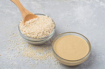 Raw sesame seeds and sesame paste on a gray concrete background. Horizontal.
