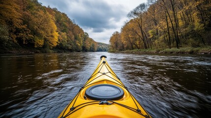 Fototapeta premium A yellow kayak is in the middle of a river. The water is calm and the sky is cloudy