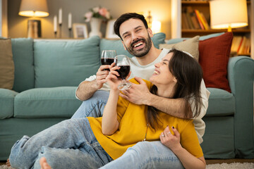 Fototapeta premium A cheerful couple enjoys a delightful moment together with their wine, creating a warm atmosphere of connection and love.