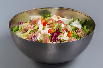 Vegetable salad with lettuce, mozzarella and jamon in metal bowl