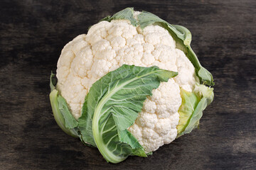Whole raw cauliflower head on a black surface