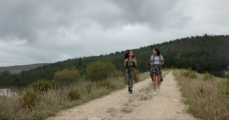 Fototapeta premium Friends, women in park and hiking in nature, walking and travel together with fun outdoor. Adventure, journey and fitness, sightseeing for tourism in environment and backpacking with trekking