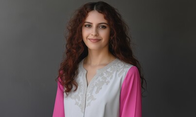 A confident European woman smiles in an embroidered blouse and black trousers, showcasing modern elegance and style