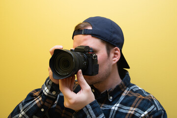 Obraz premium A male photographer in the process of taking pictures on a yellow background.