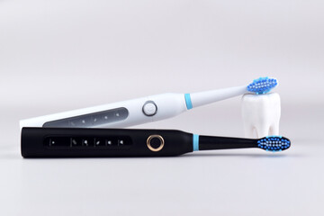 Modern electric ultrasonic toothbrush with rechargeable battery on a gray surface.