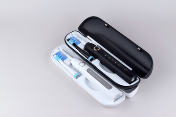 Modern electric ultrasonic toothbrush with rechargeable battery on a gray surface.