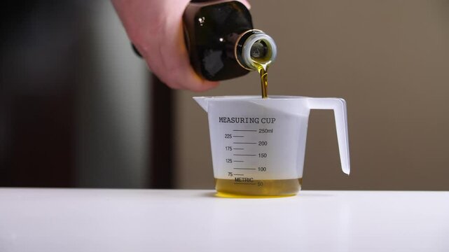 Chef pouring olive oil into measuring cup for precise cooking