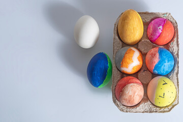 Colorful decorated Easter eggs in a cardboard box on a white background