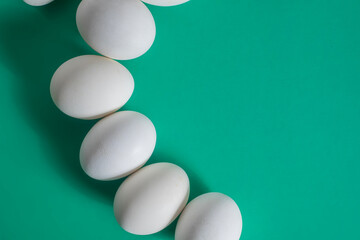 White eggs arranged on a green background with copy space for text