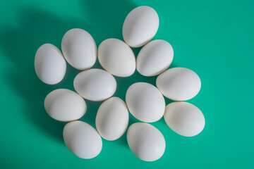 Pile of white chicken eggs against a vivid green background. for agriculture, food, nutrition, or Easter themes.