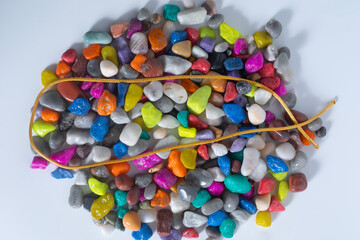 Colorful pebbles arranged with a decorative gold chain on a white background.