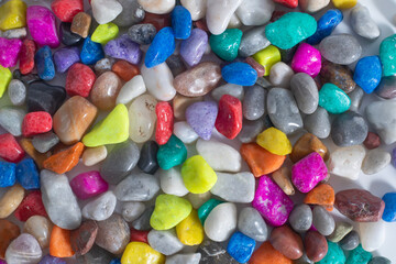 Colored polished stones in various shapes and textures on a white background.