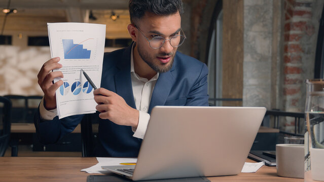 Arabian business man happy smiling guy office manager consultant male businessman greeting hello video call online meeting talking distant conference discuss papers chart graph at corporate workplace