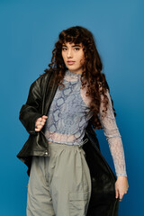 Fototapeta premium Stylish young woman exudes emotion in trendy outfit against vibrant blue backdrop