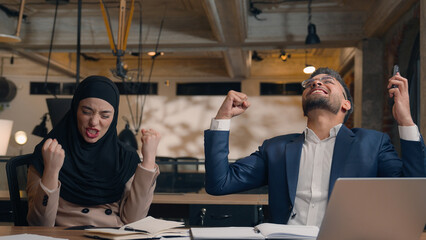 Diverse business partners office colleagues Arabian Indian man muslim woman hijab celebrate good result laptop online victory achievement success happy amazed excited businesswoman businessman winning