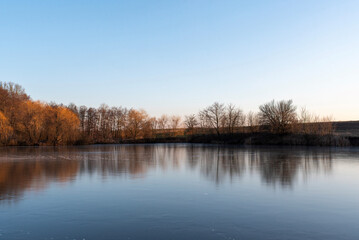 Obraz premium A lake with frozen water and trees without leaves