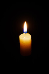 Close-up single candle burning on dark black background, candle fire flame light.