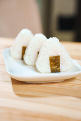 Onigiri made of rice and nori seaweed are spun on a white plate. A simple and delicious Asian snack meal.