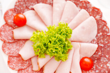 close-up. Sausage slices with lettuce leaf and cherry tomatoes. Traditional appetizer.