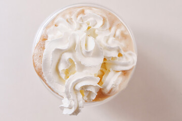 Whipped cream is squeezed out of a can onto a rotating cup of coffee on a white background. preparation of delicious invigorating and dessert drinks.