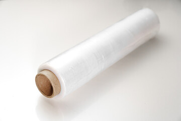 a roll of packaging stretch film on a white table. Convenient packing and transport material for groceries or moving.