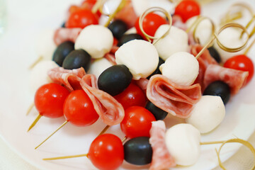 skewers with cherry tomato, sausage, olives and mozzarella cheese canapes. An original simple and delicious snack.