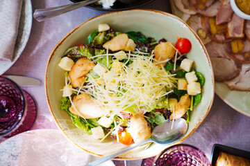 a large plate of Caesar salad on the served table. Traditional salad recipe.