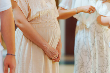 without a face. A pregnant woman in a light dress at a church service. family Orthodox traditions.