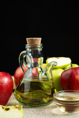 Apple cider vinegar in a glass vinegar bowl among apples