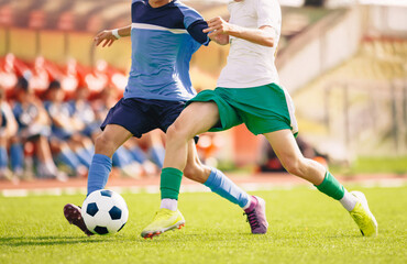 Soccer player kicking a ball on the field. Football duel between two players. Adult soccer players compete in a run. Sports competition on the stadium