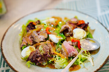 A plate of meat salad made from lettuce, quail egg, vegetables and steak. Menu for the holiday.