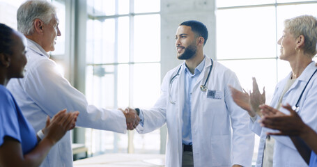 Healthcare, applause and handshake by doctors in a hospital with partnership, success or deal....