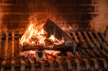 a large old brick fireplace with metal grates and a fire burning in it