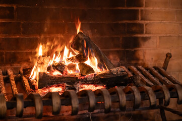 a large old brick fireplace with metal grates and a fire burning in it