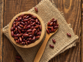 Red kidney beans in a scoop on a wooden table against a white background.