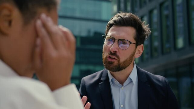 Angry authority Caucasian man businessman male boss leader yelling scolding to sad worried African American woman businesswoman female reprimand aggressive screaming problem business bullying in city