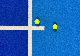  two balls and the line of a blue paddle tennis court