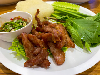 Thai sun dried, deep fried pork with sticky rice, stink beans, chili sauce and vegetables and herbs