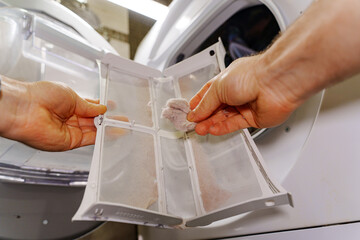 cleaning the filter in the dryer. Modern household appliances for washing and drying clothes. Care...