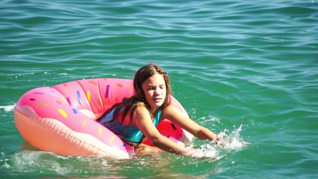 Summer Vacation Woman floats on an inflatable donut mattress, a water toy swim ring. Positive happy woman relaxing and enjoying family summer travel holidays vacation on the sea. Slow motion