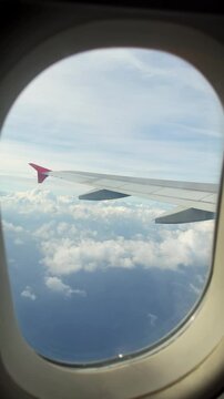 View from airplane window at beautiful fluffy clouds. Travel concept, vertical footage. High quality 4k footage