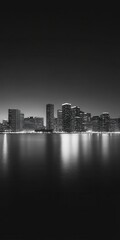 Fototapeta premium a coastal city at twilight. The skyline, lights glowing softly, is reflected in the water