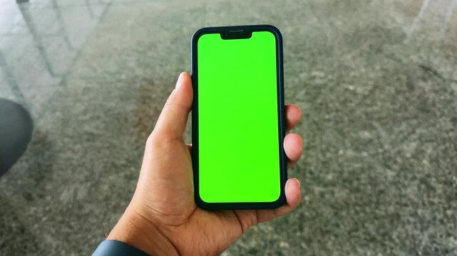 Hands of a man holding a smartphone touching the phone with a vertical green screen on the background of a walk in the airport terminal. High quality 4k footage