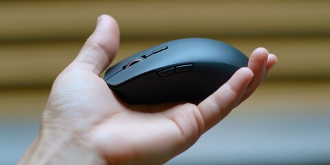 Fototapeta premium A hand holding a black computer mouse