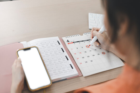 Planning and scheduling meeting calendars, events, time management, reminders and notifications about important events. Woman circling on work calendar.
