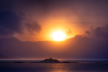 Obraz premium A beautiful sun shining over the snowy mountains and fjord during the first day of arctic winter. Arctic nature in Scandinavia during winter season.