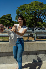 Young latin woman pulling a tote bag on a bridge in a park
